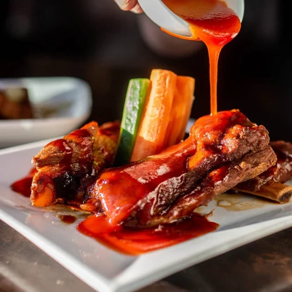 Red sauce poured over crispy pork with cucumber and carrot sticks.