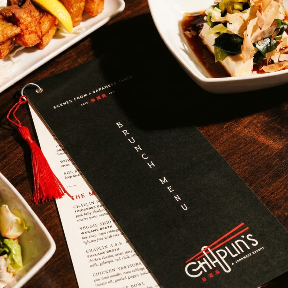 CHiP’N Japanese restaurant menu surrounded by assorted plated dishes on a dark wooden table.